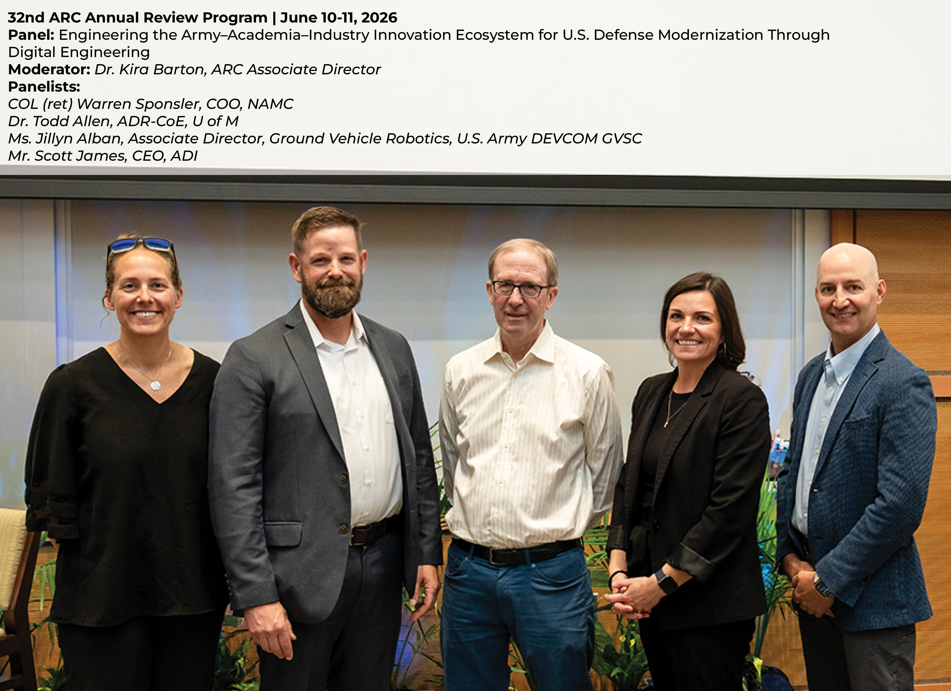 Four panelists and one moderator standing together in an auditorium, posing for a photo after a panel discussion at a formal event.