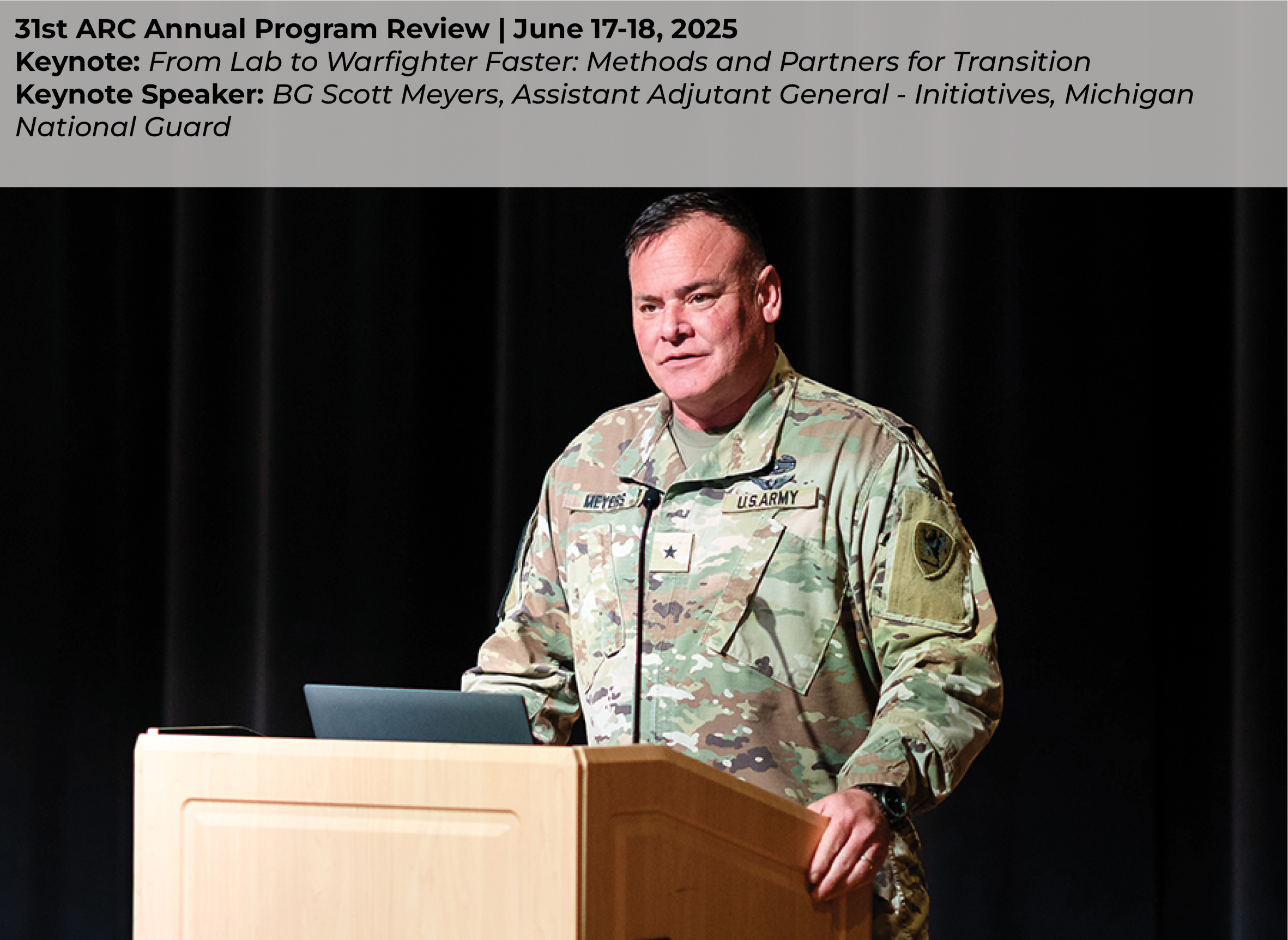 BG Scott Meyers delivering his keynote presentation “From Lab to Warfighter Faster: Methods and Partners for Transition” at a podium on stage. BG Meyers is wearing his military uniform and speaking at a podium in front of black curtains.