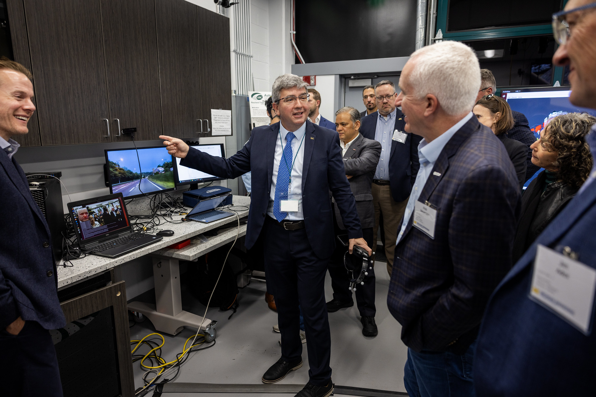 Prof. Bogdan Epureanu standing in front of a computer screen explaining to participants the contents and technology on the screen