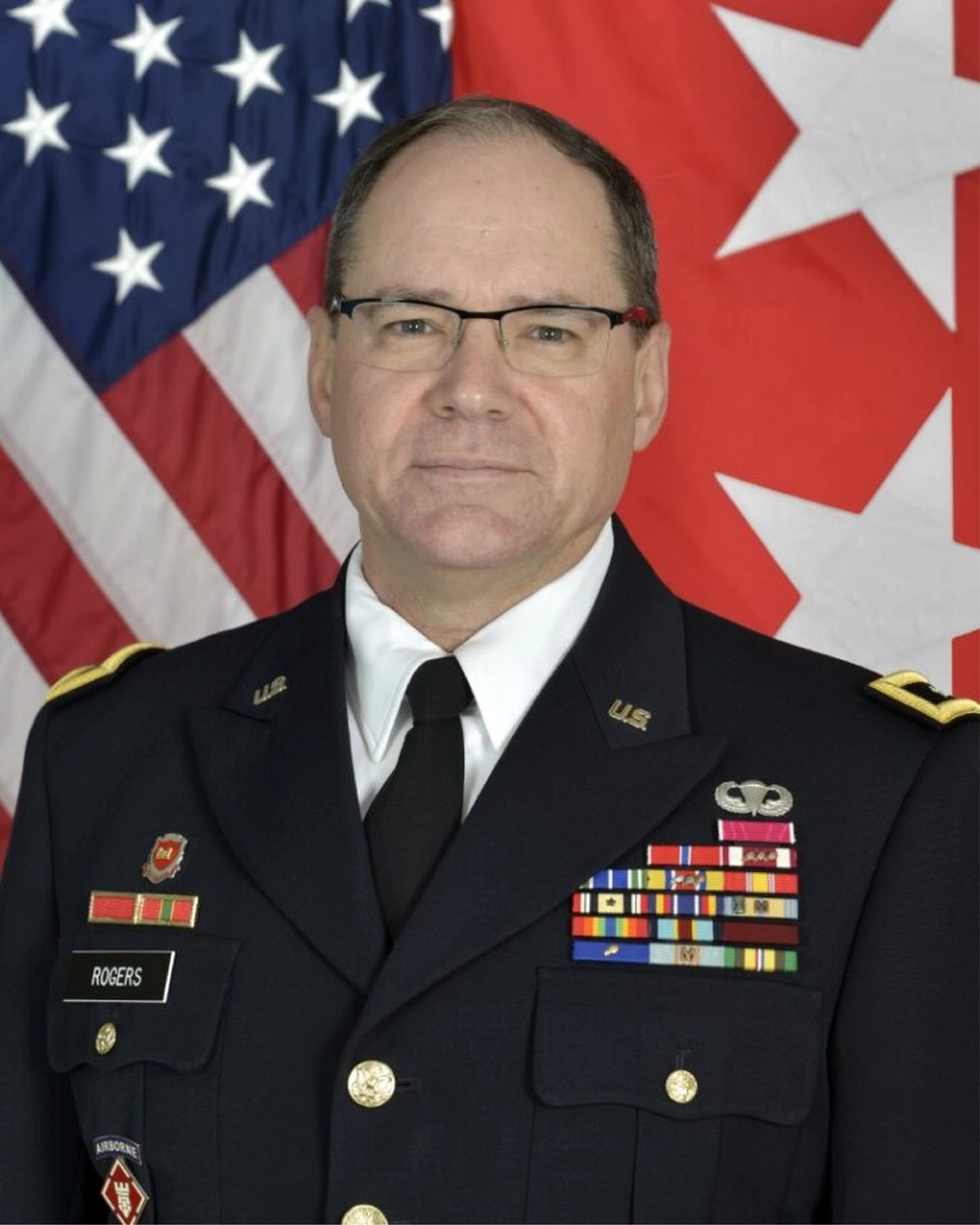 Major Generals. Rogers is standing in front of a flag in a military uniform.