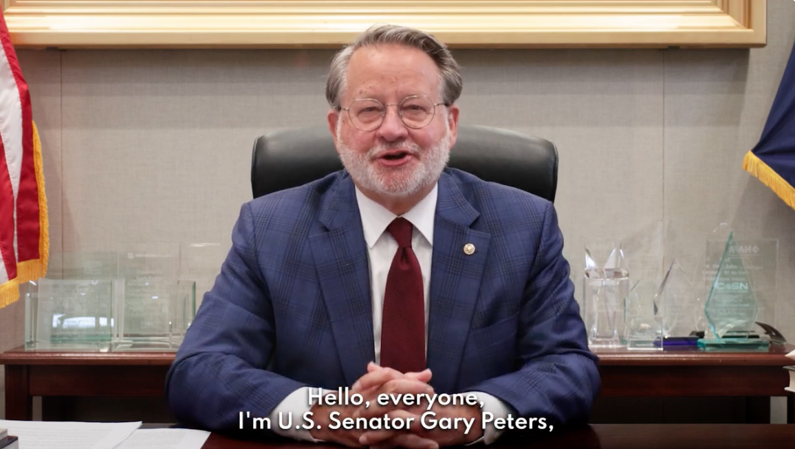 U.S. Senator Gary Peters sitting at desk talking. 